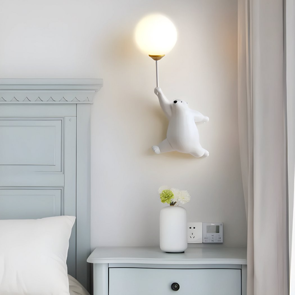 Applique murale avec boule lumineuse et ourson blanc accrochée au-dessus d'une table de chevet à côté d'un lit