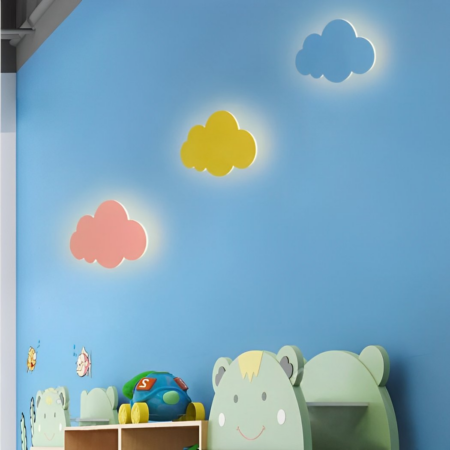 Il y a trois appliques murales en forme de nuage : une bleue, une rose et une jaune, accrochés sur un mur bleu dans une chambre d'enfant