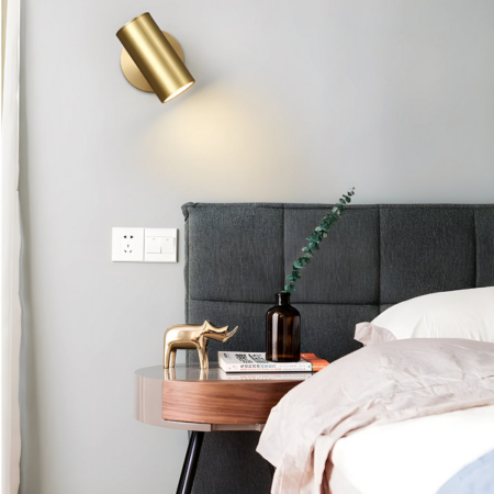 Applique murale dorée en tube à angle réglable accrochée dans une chambre