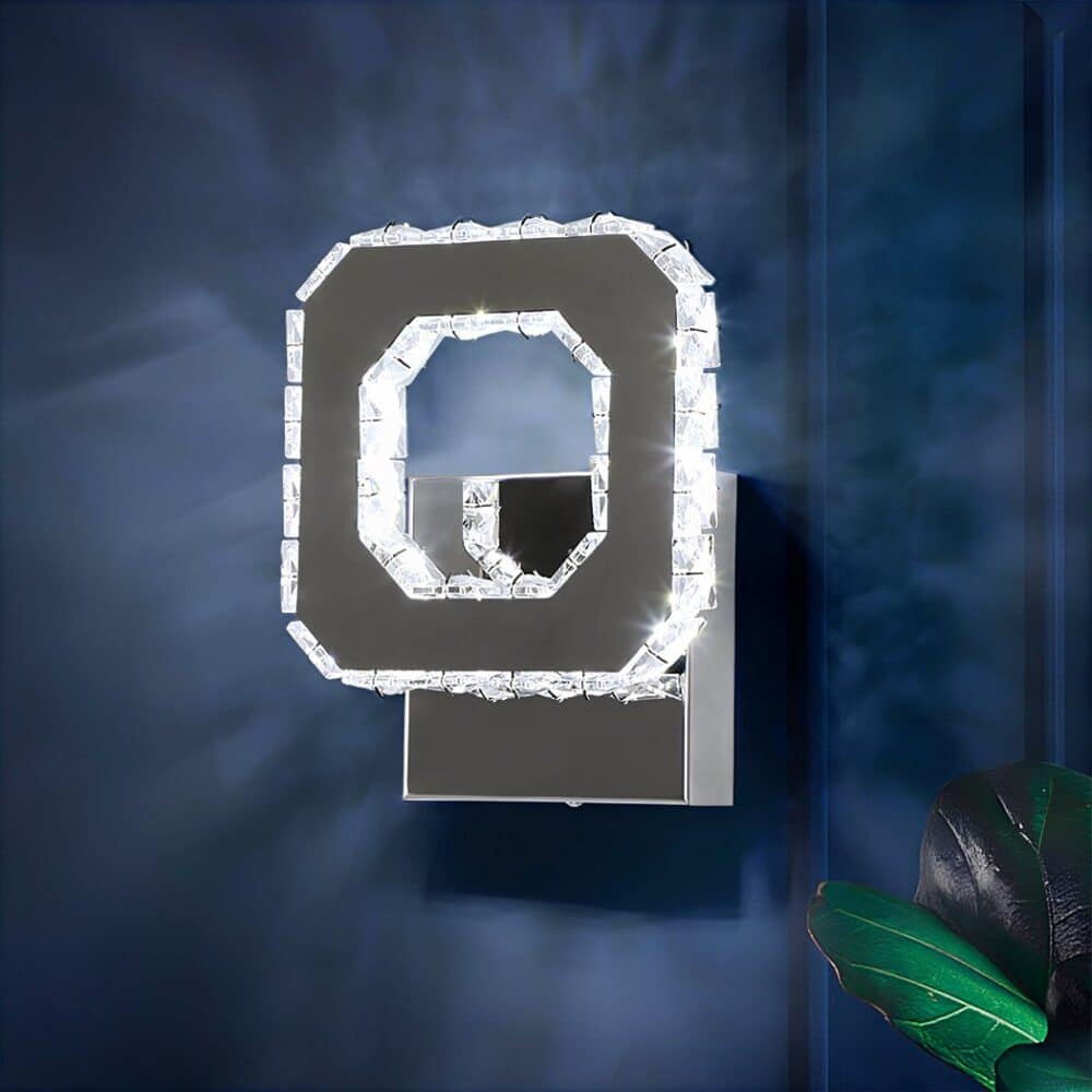 Applique murale carrée creuse argentée avec un effet diamants sur les contours intérieurs et extérieurs. Fixée sur un fond bleu et elle diffuse une lumière froide.