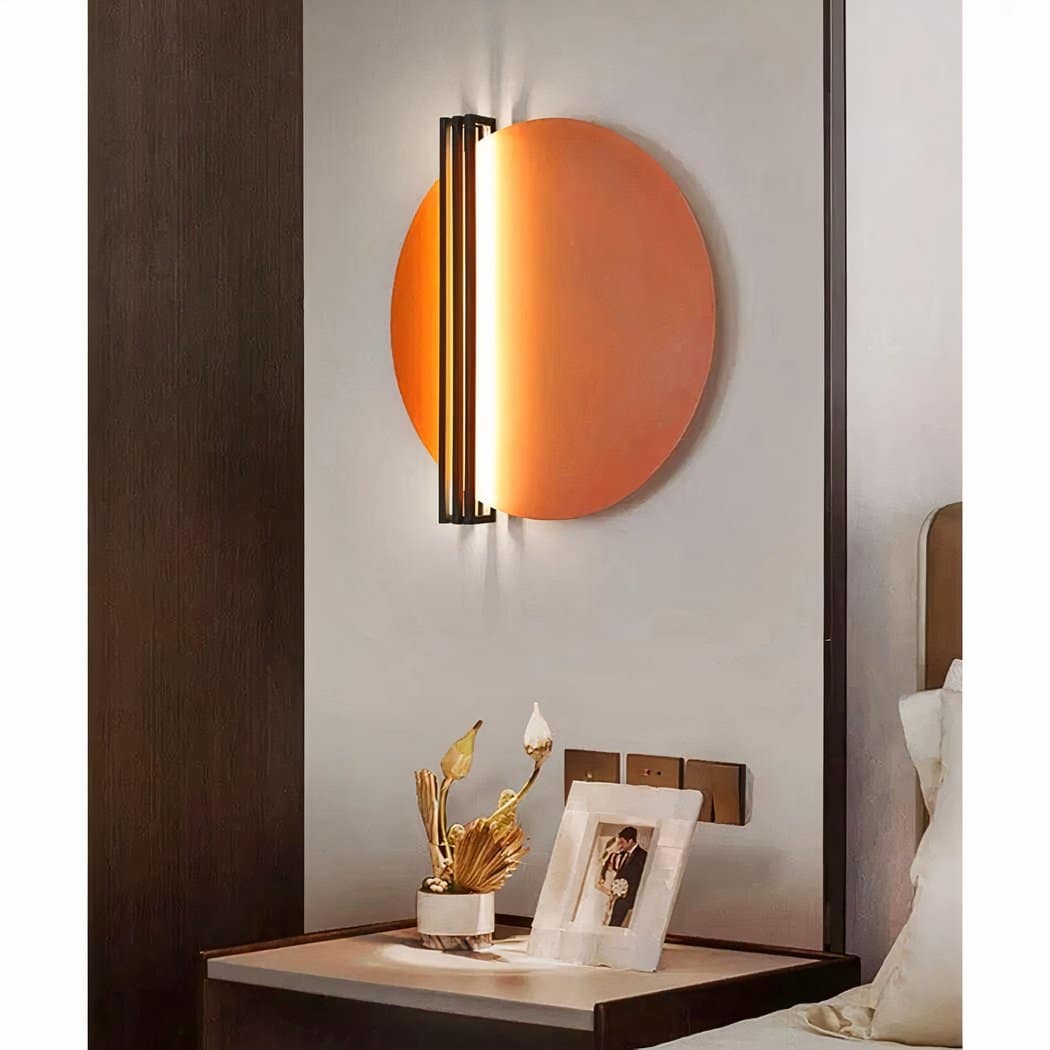 on voit dans une chambre au dessus d'une table de nuit une applique murale circulaire de style scandinave orange