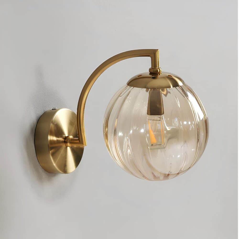 Applique murale style vintage avec structure dorée et boule en verre fumée avec des stries verticales. L'applique murale est fixée sur un mur gris.