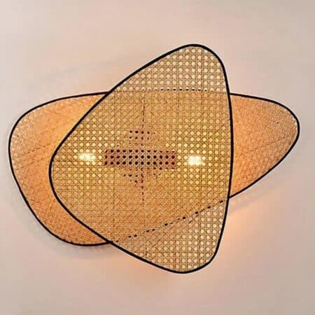 on voit sur un mur clair une applique murale en cannage avec rebord noir