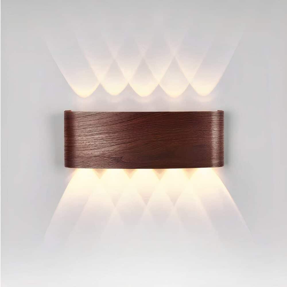 Applique murale en forme de rectangle arrondi imitation bois foncé et diffusant la lumière au-dessus et en-dessous en forme de plusieurs V qui se chevauchent sur fond gris.