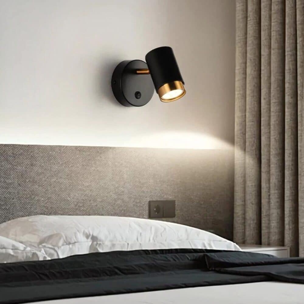 on voit dans une chambre grise au dessus d'une tête de lit une applique murale noire moderne