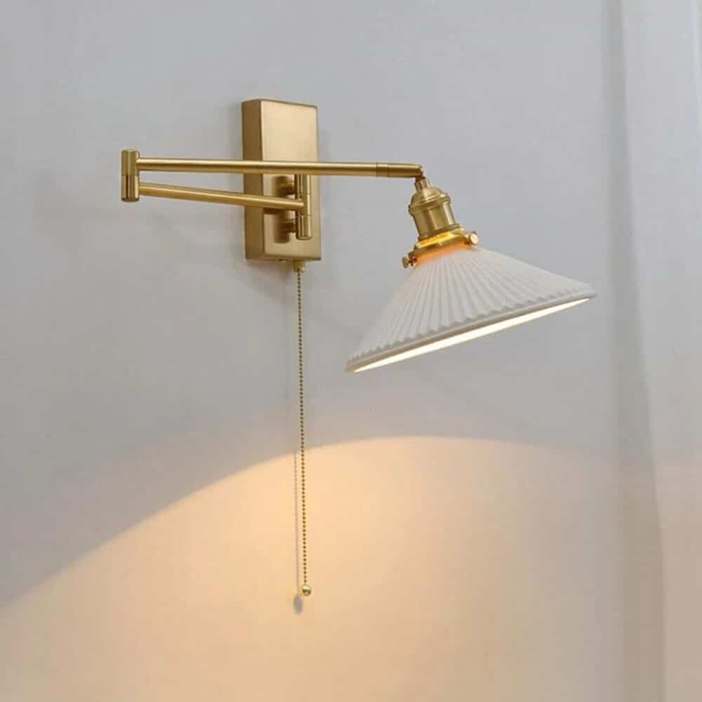 on voit une applique murale de couleur blanche et laiton posée sur un mur gris clair