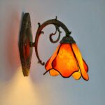 on voit une applique murale en forme de fleur suspendue orange dans le style Tiffany