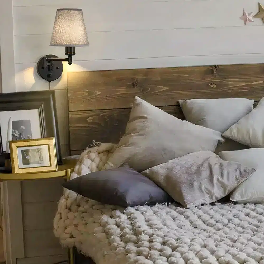 Une applique murale filaire à bras pliant en métal noir fixée dans une chambre