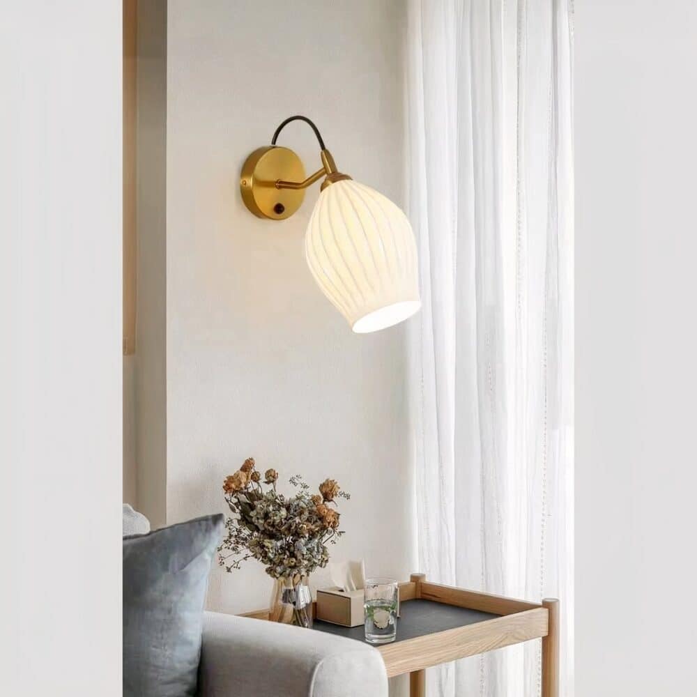 Applique murale en céramique blanche jolie forme arrondie fixée sur un mur de salon, à côté d'un canapé.