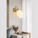 Applique murale en céramique blanche jolie forme arrondie fixée sur un mur de salon, à côté d'un canapé.