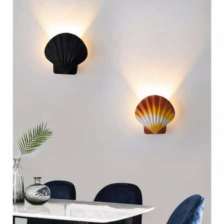 on voit dans un salon aux murs gris deux appliques murales en forme de coquille saint jacques une marron et une noire