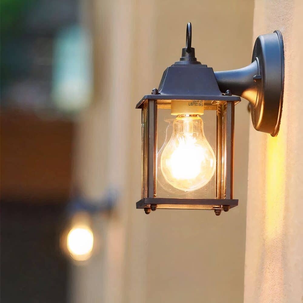 on voit sur un mur extérieur une applique murale en forme de lanterne pour extérieur allumée