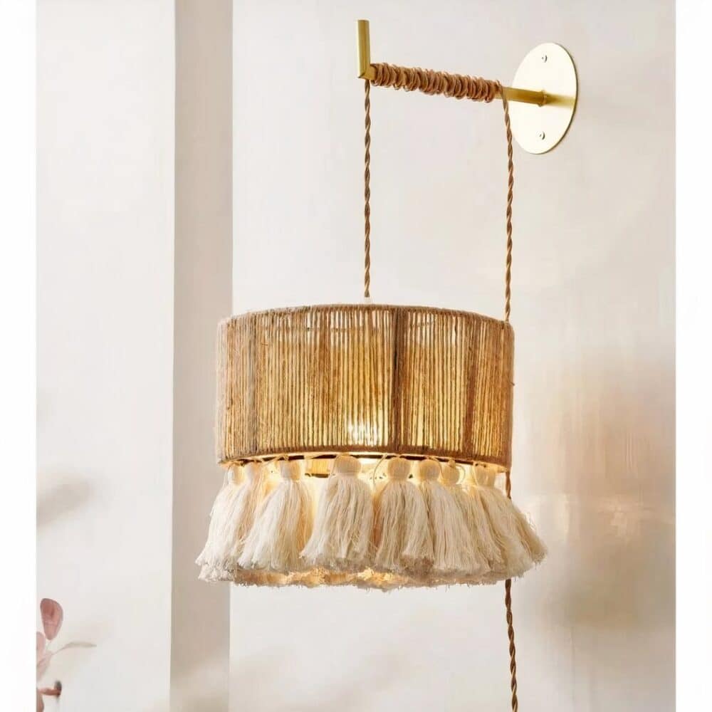 on voit dans une pièce aux murs clairs une applique murale en osier et à franges dans le style bohème