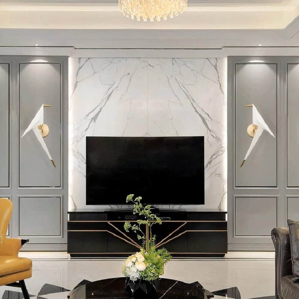 on voit dans un salon aux murs gris une télé éteinte au milieu et sur chaque côté une applique murale origami en forme d'oiseau blanc