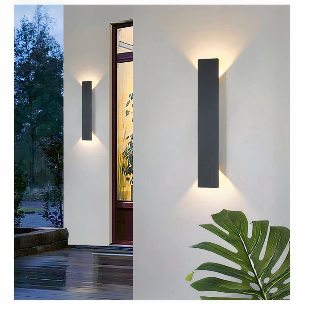 on voit sur une terrasse sur un mur blanc une applique murale rectangulaire et verticale et moderne noire pour extérieur