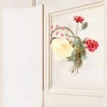 Applique murale rétro en fer forgé et en forme de fleur allumée et fixée sur un mur blanc.