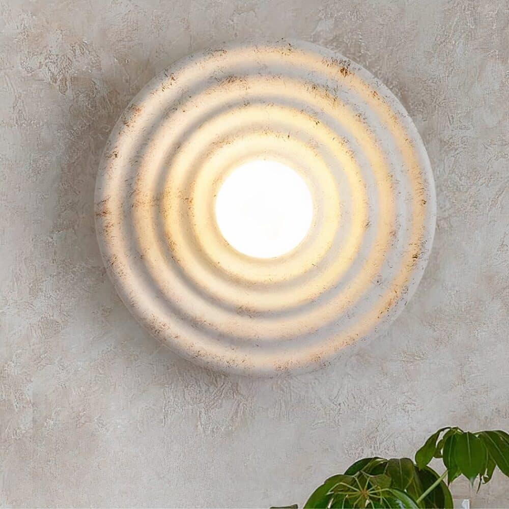 on voit sur un mur gris une applique murale ronde effet pierre naturelle dans le style bohème