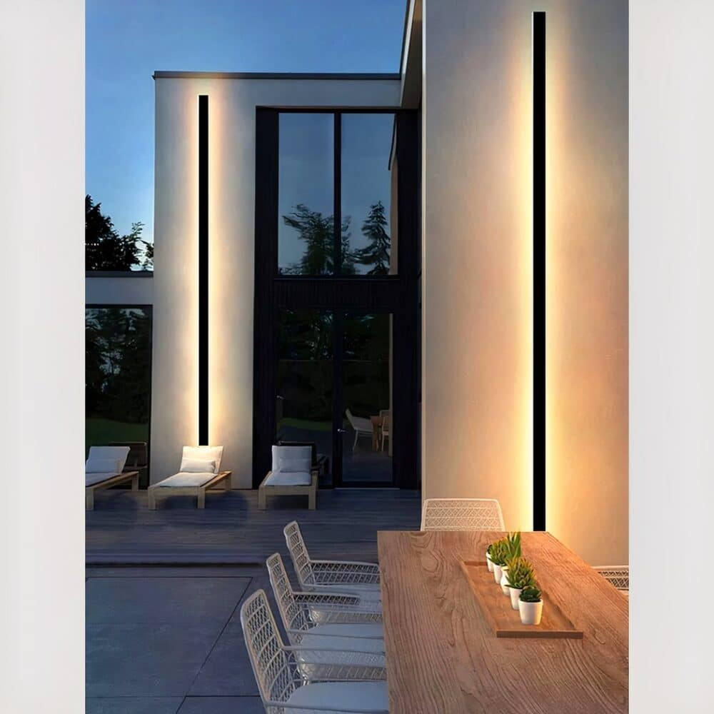 Applique murale solaire design épuré accrochée sur le mur d'une terrasse et allumée.