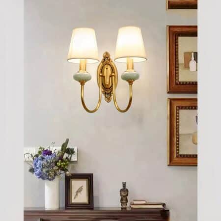 Applique murale vintage en céramique et abat-jour en tissu allumée et fixée au mur d'un salon, au-dessus d'une commode.